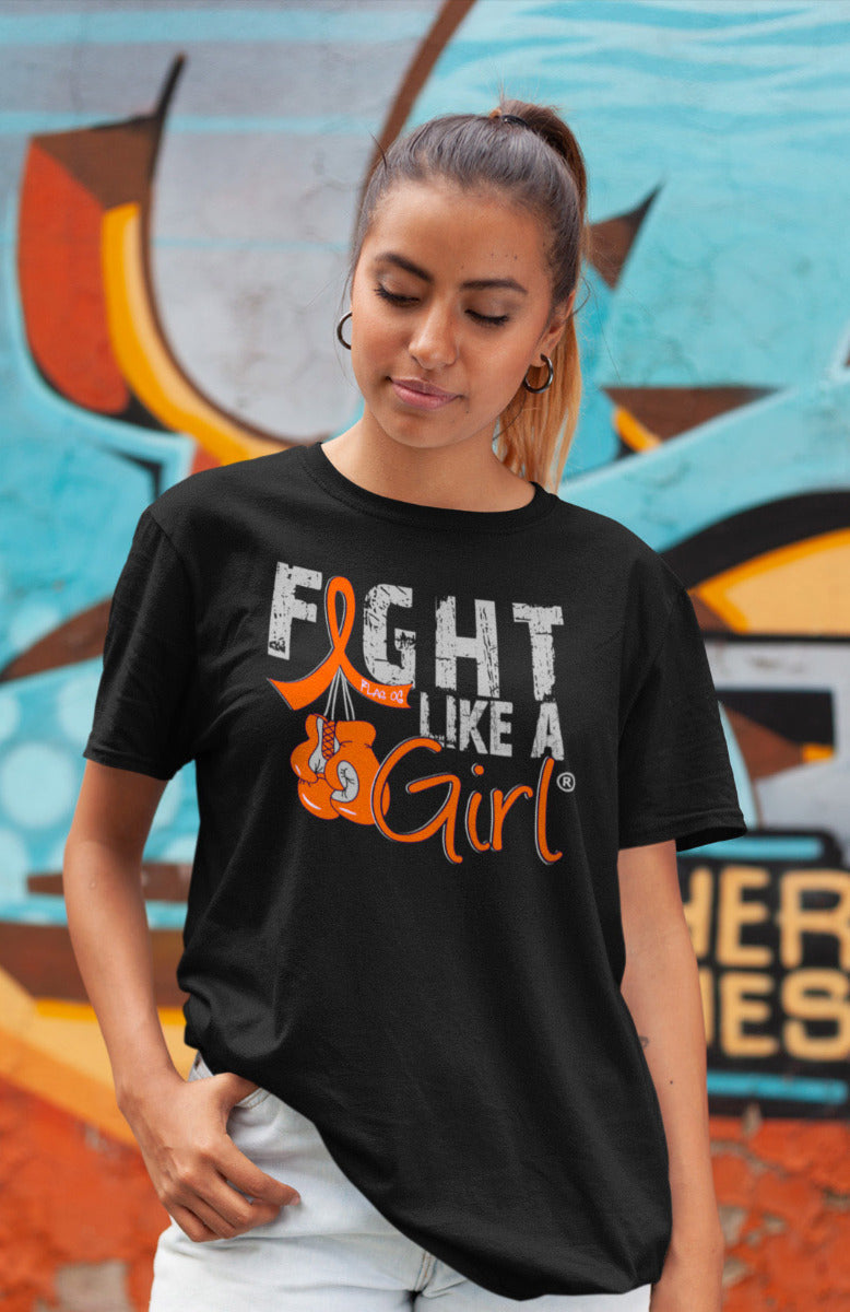 Woman wearing a black unisex t-shirt with the Fight Like a Girl Knockout design in orange on the front. The design says "Fight Like a Girl" and includes boxing gloves hanging from an orange awareness ribbon.