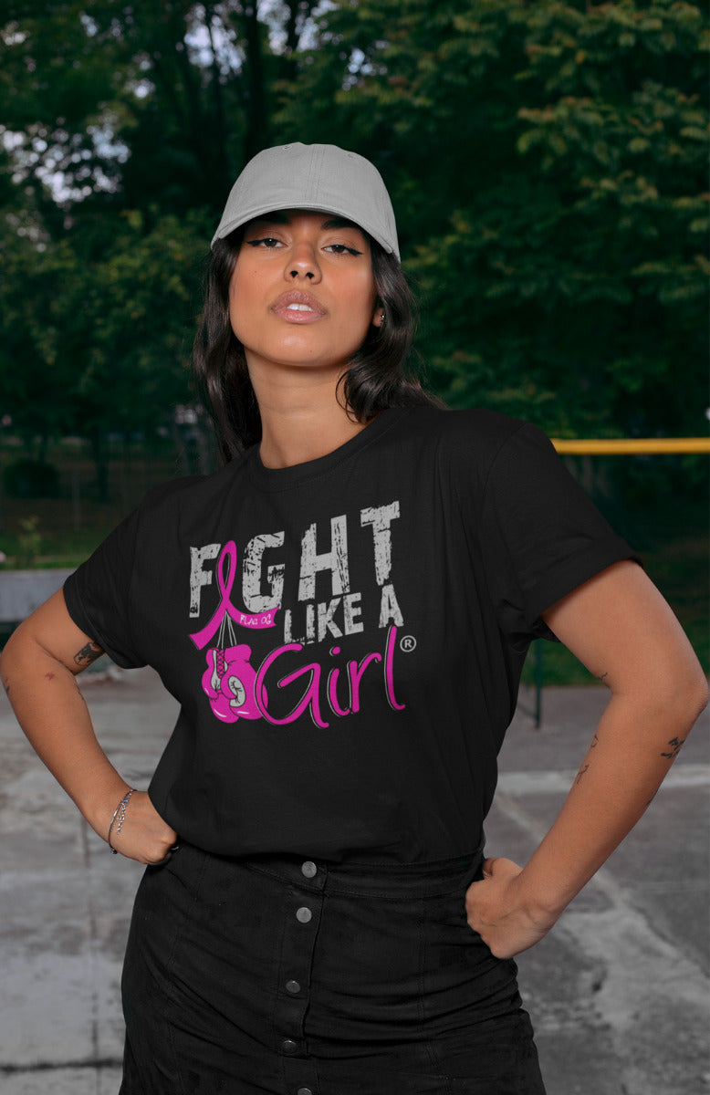 Woman wearing a black unisex t-shirt with the Fight Like a Girl Knockout design in pink on the front. The design says "Fight Like a Girl" and includes boxing gloves hanging from a pink awareness ribbon.