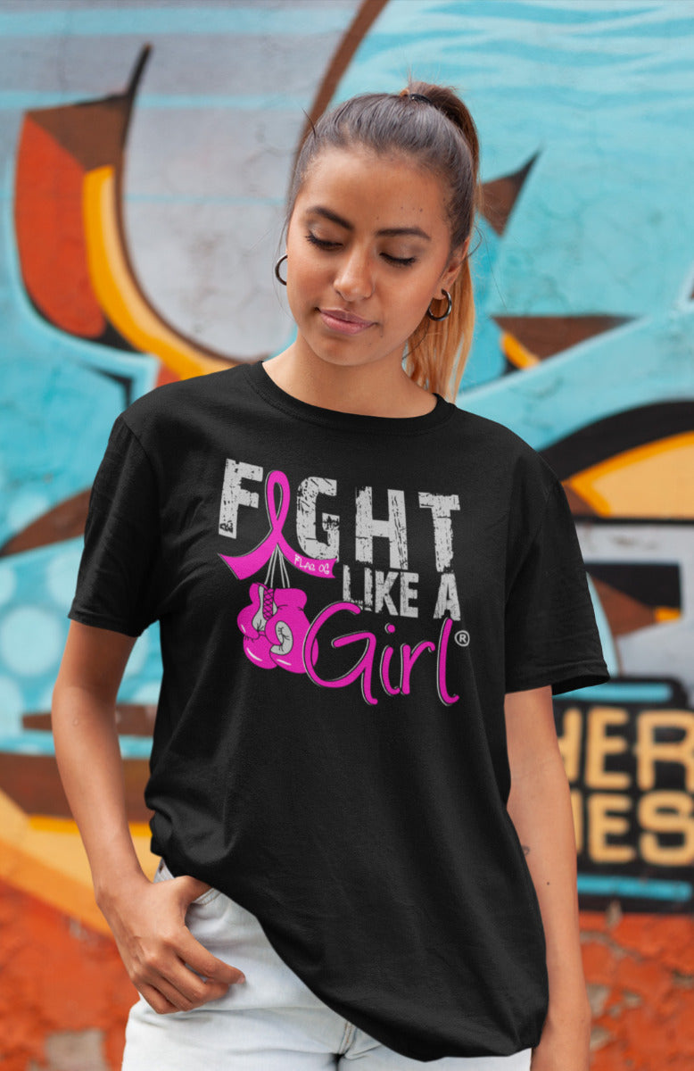 Woman wearing a black unisex t-shirt with the Fight Like a Girl Knockout design in pink on the front. The design says "Fight Like a Girl" and includes boxing gloves hanging from a pink awareness ribbon.