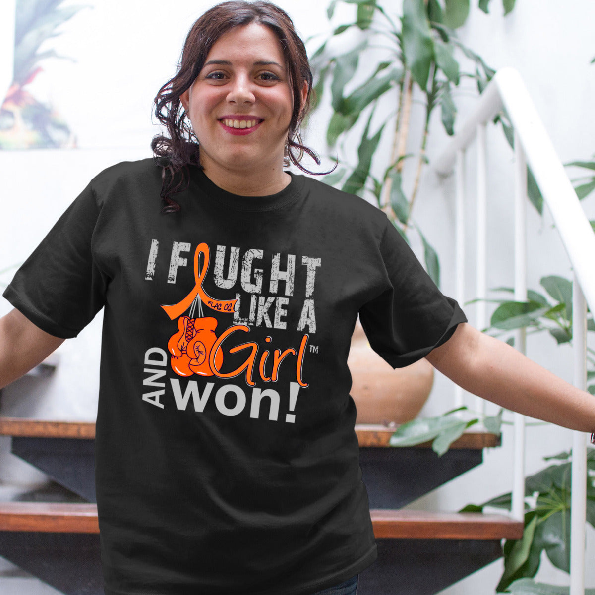Woman wearing a black unisex t-shirt with the I Fought Like a Girl Knockout design in orange printed on it.