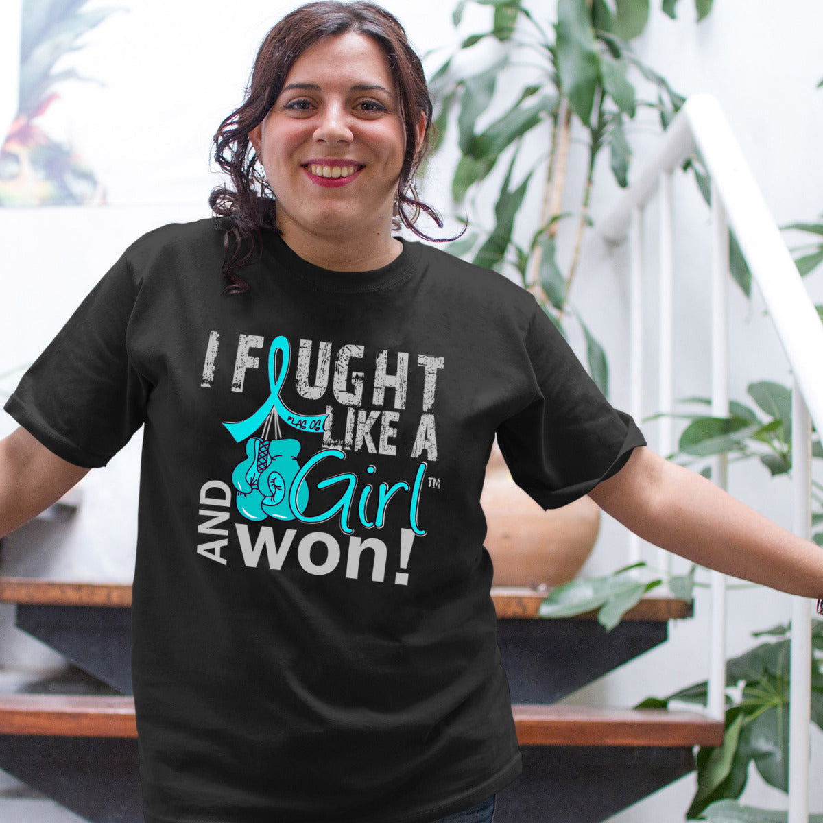 Woman wearing a black unisex t-shirt with the I Fought Like a Girl Knockout design in teal printed on it.